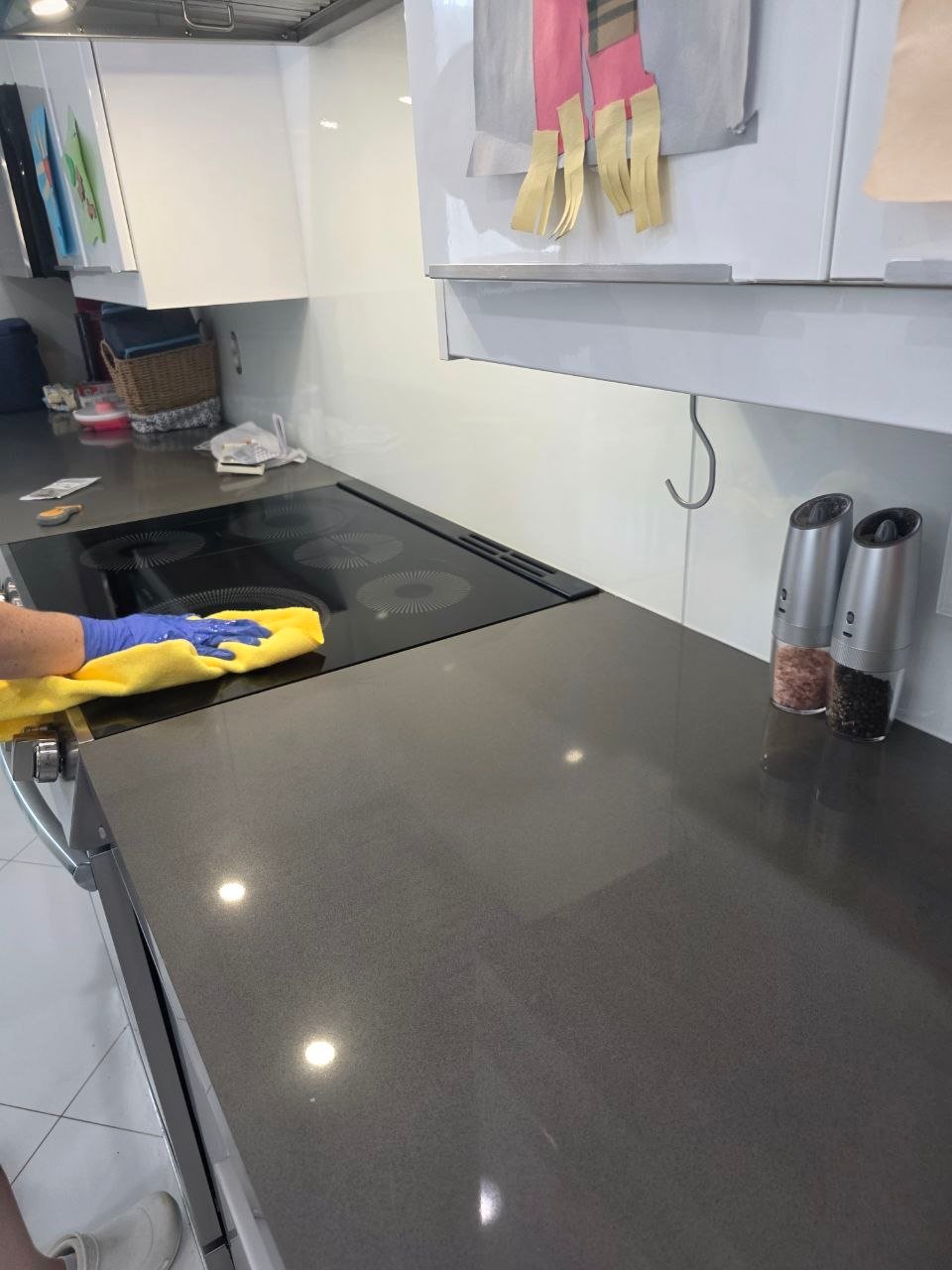 A gloved Cleanantsy team member wiping a kitchen cooktop
