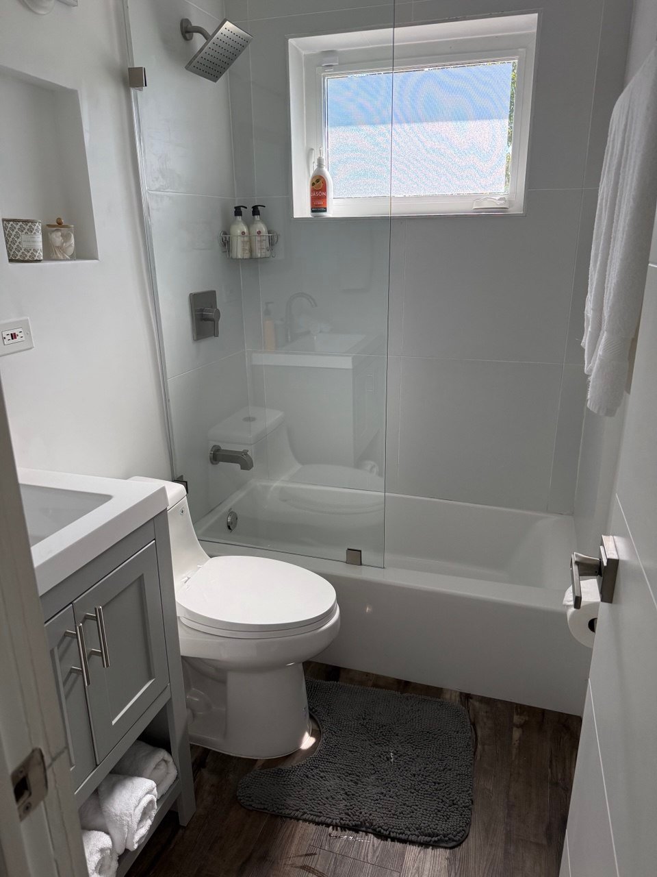 White bathroom with glass shower enclosure in a home cleaned by Cleanantsy